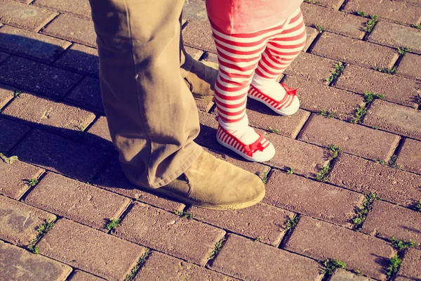 father helping little daughter to make first steps