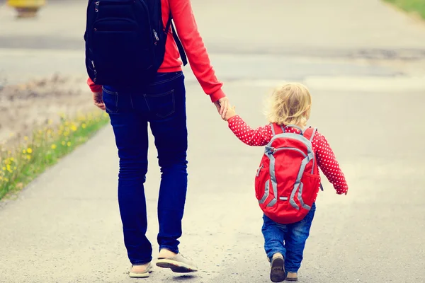 Mother holding hand of little daughter with backpack — Stock Photo, Image