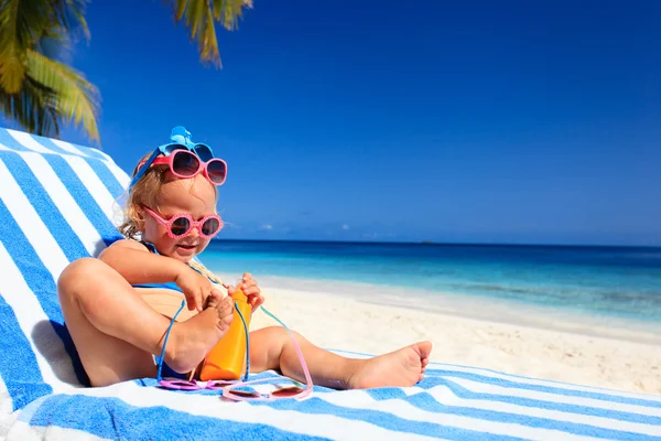 Roztomilá holčička se snaží na sluneční brýle na pláži — Stock fotografie
