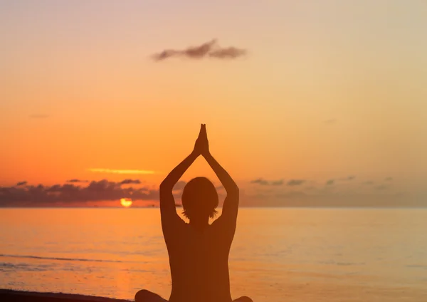 Silhouette de jeune homme faisant du yoga au coucher du soleil — Photo