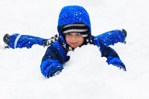 Little boy having fun in winter snow