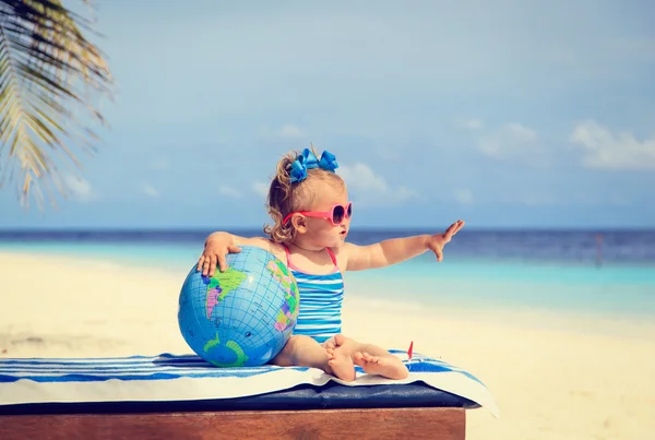 Little girl with globe and toy plane on beach — Stock Photo, Image