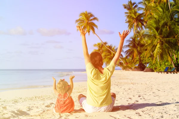 Feliz padre e hija pequeña manos arriba en la playa — Foto de Stock