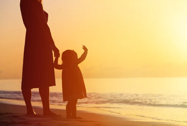 Mère et petite fille marchant sur la plage au coucher du soleil — Photo