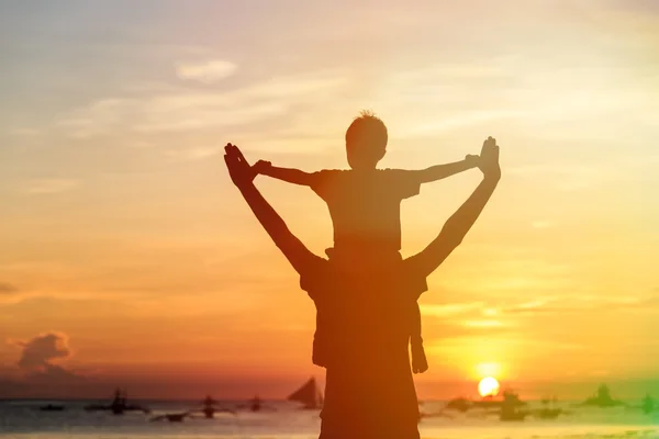 Счастливые отец и сын на закатном пляже — стоковое фото