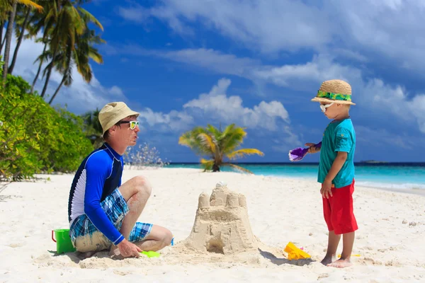 Vader en zoon gebouw zand kasteel op strand — Stockfoto