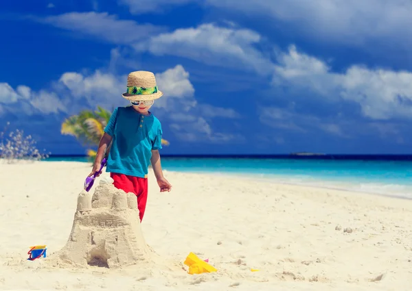 Маленький мальчик строит замок на пляже — стоковое фото