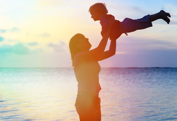 Moeder en baby plezier in sunset beach — Stockfoto
