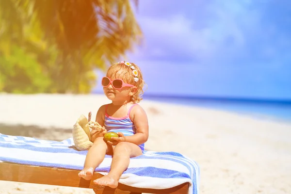 Menina bonito com saco e coco na praia — Fotografia de Stock