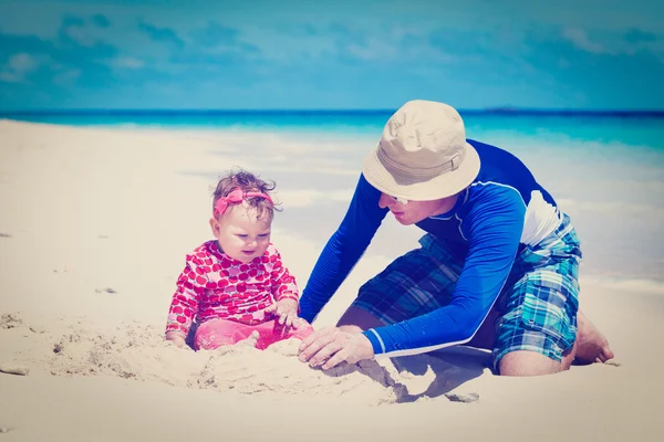 Батько і маленька дочка грають з піском на пляжі — стокове фото
