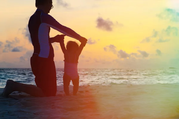 Vater und kleine Tochter spazieren am Sonnenuntergangsstrand — Stockfoto