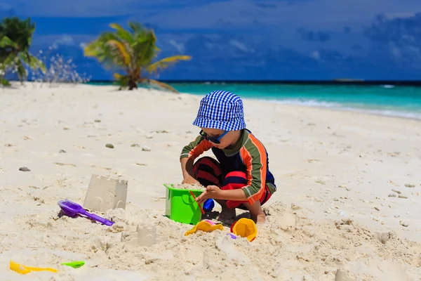 Küçük çocuk kum ile tropik sahilde oynarken — Stok fotoğraf
