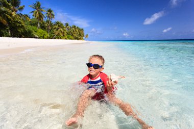 little boy swimming found shell on beach