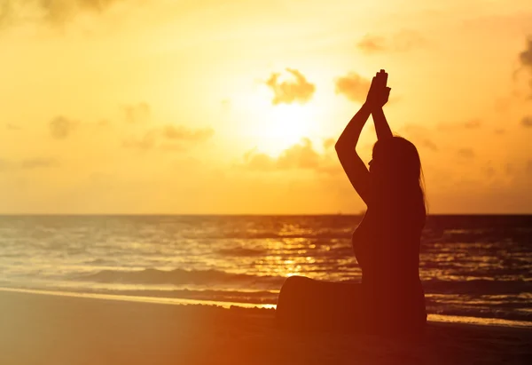 Žena meditace na pláži při západu slunce — Stock fotografie