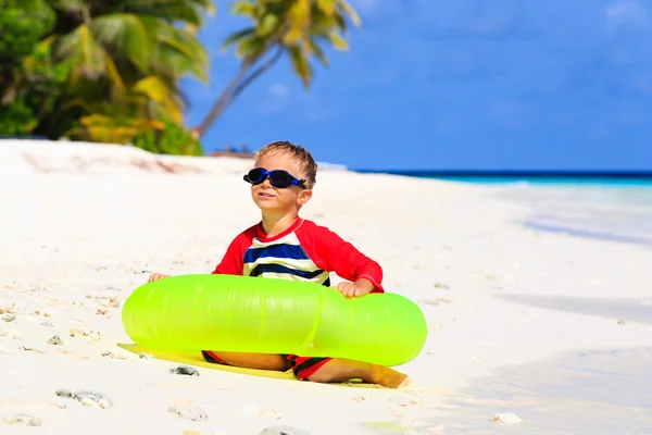 Malý chlapec hraje s životem kroužkem na tropické pláži — Stock fotografie