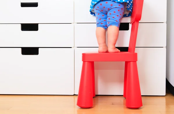 Kids safety concept- little girl climb on chair — Stock Photo, Image