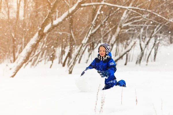 Netter kleiner Junge baut Schneemann im Winter — Stockfoto
