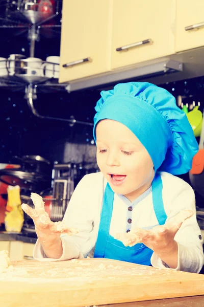 Petit garçon pétrissant la pâte dans la cuisine — Photo