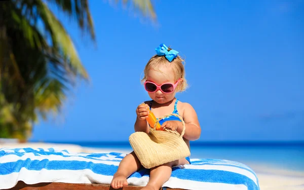 Menina bonito com creme protetor solar na praia — Fotografia de Stock