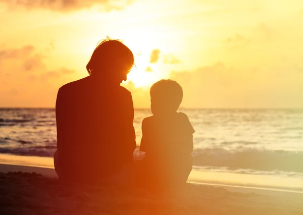 Padre e figlioletto guardando il tramonto sulla spiaggia — Foto Stock