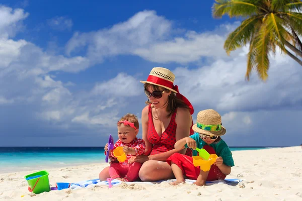 Mutter und Kinder spielen am Sandstrand — Stockfoto