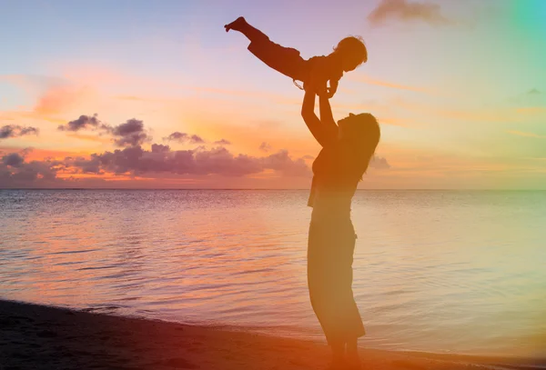 Mère et bébé amusant au coucher du soleil plage — Photo