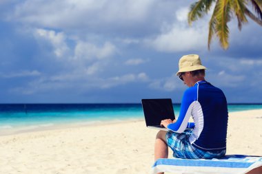 adam ile tatil tropikal üstünde laptop