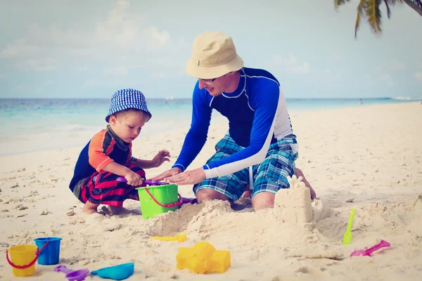 Отец и сын строят песчаный замок на пляже — стоковое фото