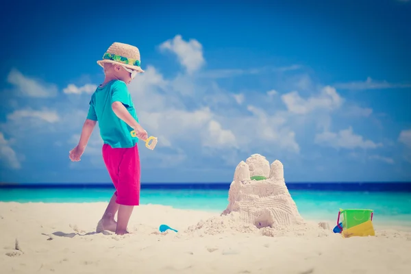 Маленький мальчик играет с песком на тропическом пляже — стоковое фото