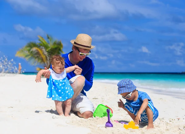 Baba ve çocukları tropikal sahilinde Kumdan kale yapma — Stok fotoğraf