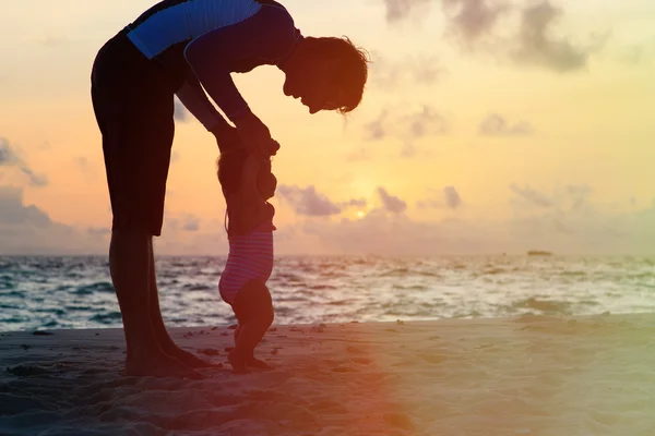 Vater und kleine Tochter spazieren am Sonnenuntergangsstrand — Stockfoto