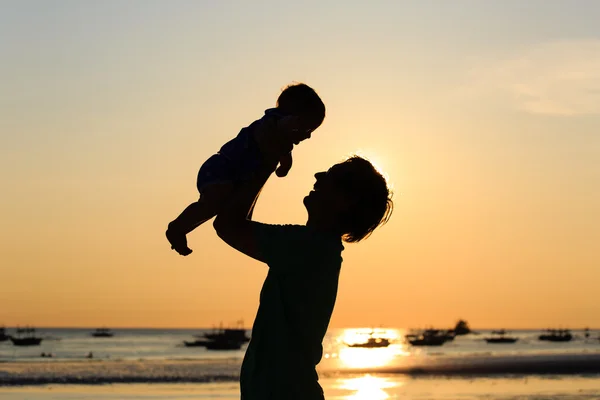 Vader en kleine dochter silhouetten op zonsondergang strand — Stockfoto