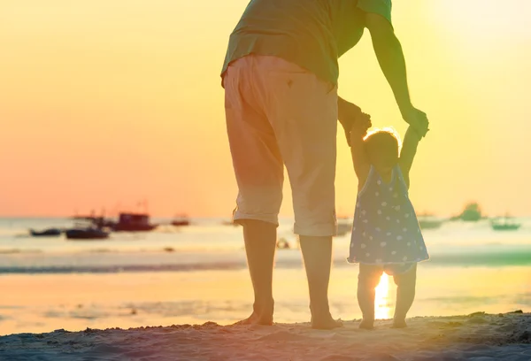 Vader en dochtertje lopen op sunset beach — Stockfoto