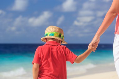 Anne ve oğlu plaj tatilinde el ele tutuşuyorlar.