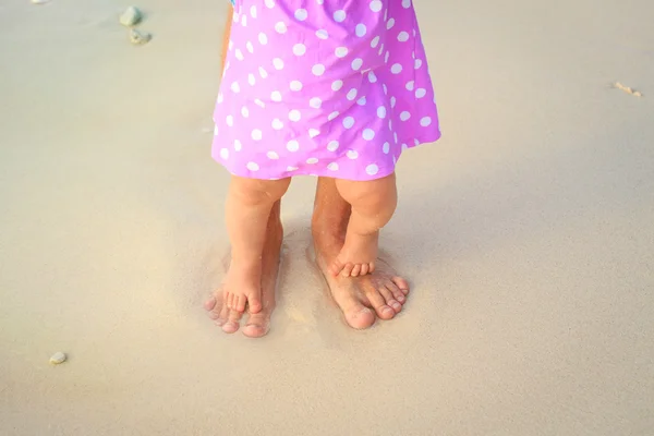 father and little daughter feet on a tropical beach