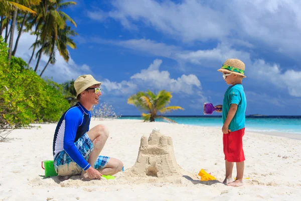 Père et fils construisant château sur la plage de sable — Photo