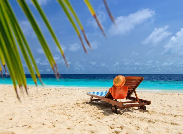 Sombrero de paja y bolso en una silla de salón en la playa de arena — Foto de Stock