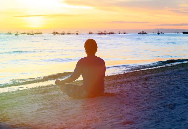 Silhueta de homem meditando na praia do pôr do sol — Fotografia de Stock