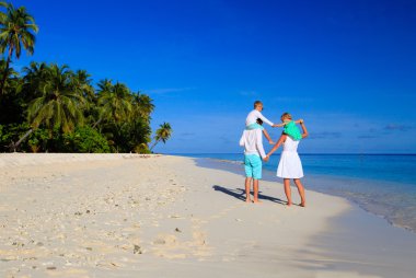 Kumsalda yürüyen iki çocuklu genç aile