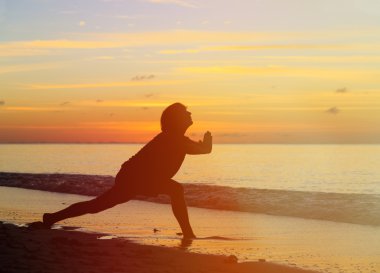 Sunset Beach yoga yaparken genç adam silüeti