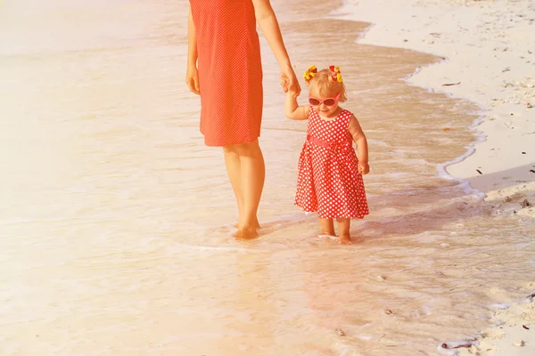 Moeder en kleine dochter lopen op zomer strand — Stockfoto