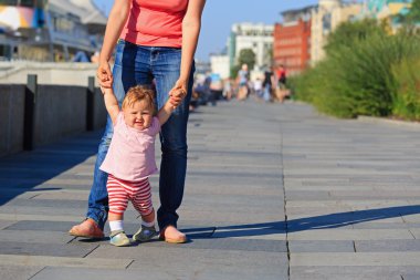 Anne ve bebek şehir parkta yürümeyi öğrenme