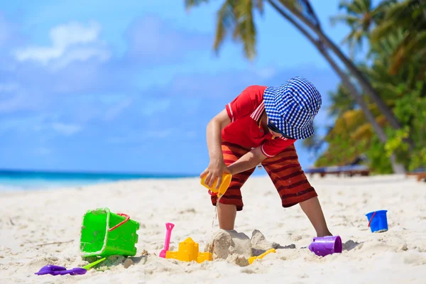 Menino brincando com areia na praia — Fotografia de Stock