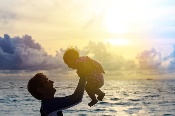 Silhouettes père et petite fille sur la plage du coucher du soleil — Photo