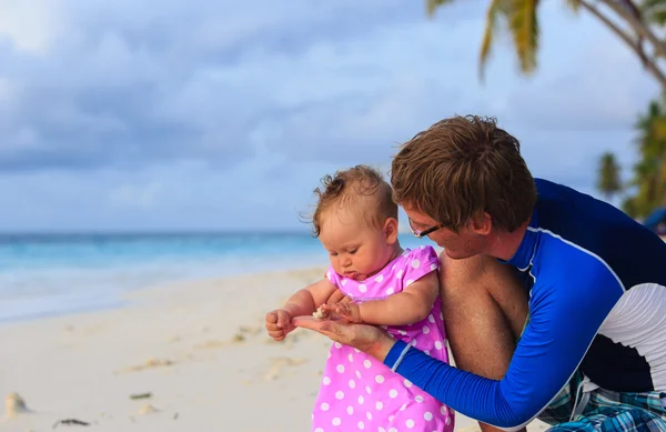 Vader en baby aanraken zeeschelp op strand — Stockfoto