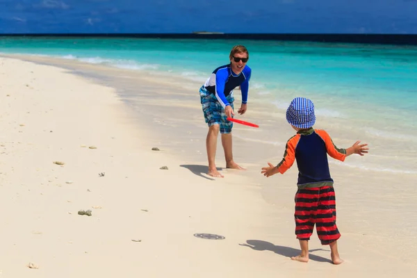 Отец и сын играют с летающим диском на пляже — стоковое фото