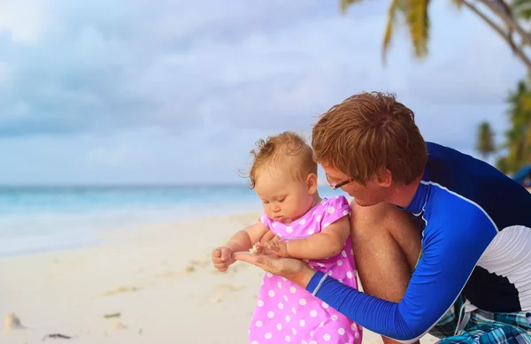 Pai e bebê tocando concha na praia — Fotografia de Stock