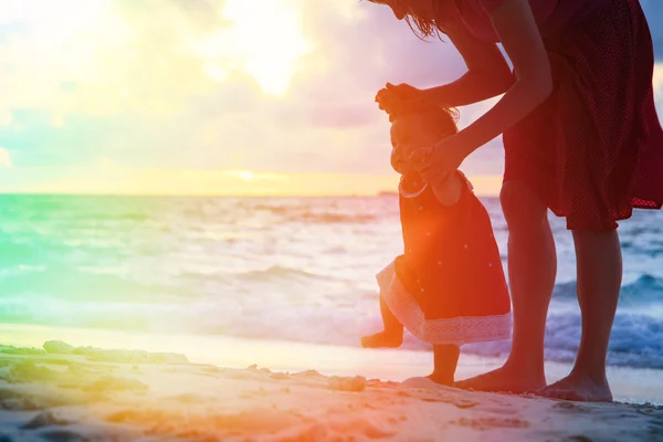 mother and little daughter walking on sand beach