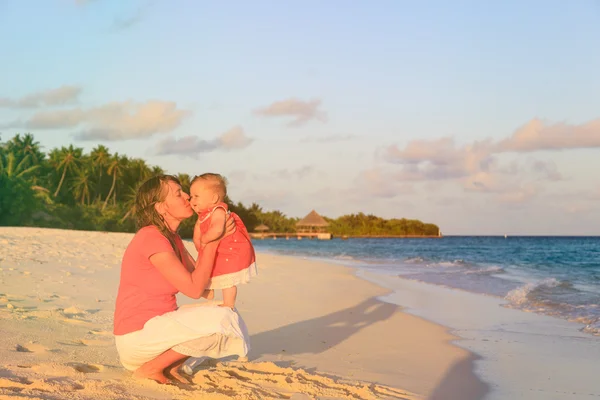 Madre besando a su hijita al atardecer playa — Foto de Stock