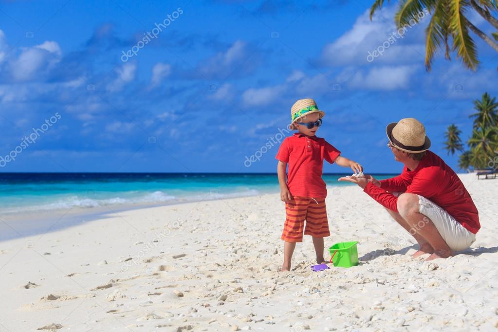 Father and son collecting shells on the beach Stock Photo by ...